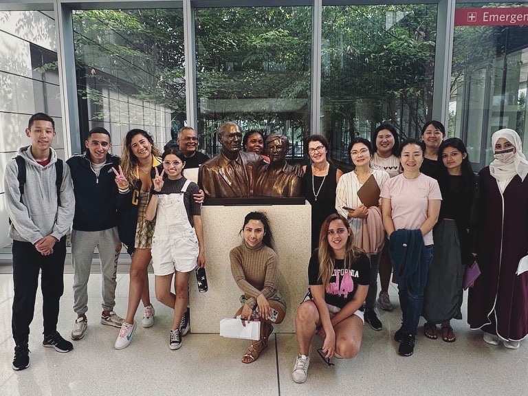 Picture of a group of students in a building standing around a statue
